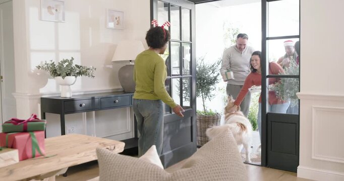 African American woman hearing knock at front door, walking, greeting friends carrying covered dish