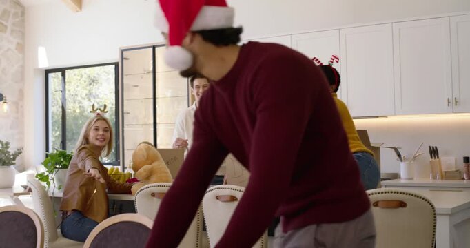 Diverse friends with holiday hats packing DONATION boxes in kitchen after board arrival for charity