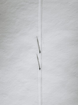 Aerial view of two cross-country skiers gliding across a vast, pristine snow-covered landscape in Suomussalmi, Kainuu, Finland.