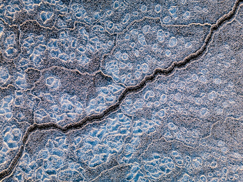 Aerial view of intricate ice patterns and cracks on a frozen river surface in Porvoo, Uusimaa, Finland.