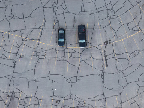 Aerial view of two vehicles parked in a cracked asphalt parking lot in Wasilla, Alaska, United States.