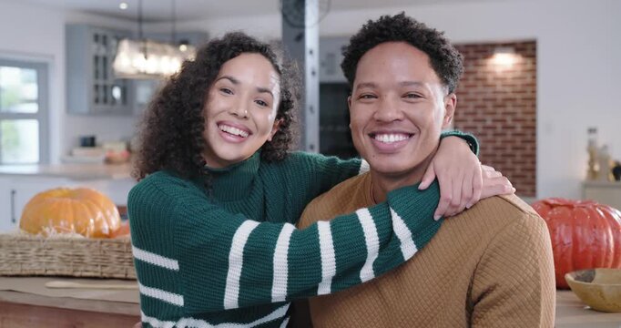 African American couple, woman leaning, wrapping arm around him at kitchen table with pumpkins