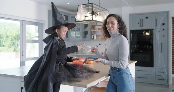 African American mom-child in hat facing each other playing RPS on kitchen island for fun, pumpkins