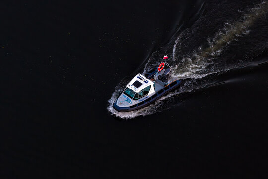Aerial view of a Polish police boat patrolling dark water.