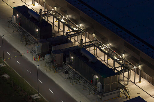 Aerial view of backup diesel generators installed outside a large AI data center at night.
