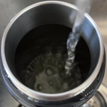 Water pouring into metal container close up water conservation