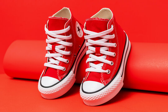 Pair of red Converse high top sneakers stands against a vivid backdrop.
