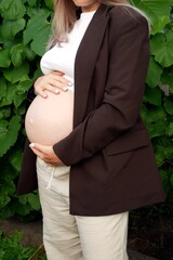 A young woman holding her bare pregnant belly ,the joy of motherhood.