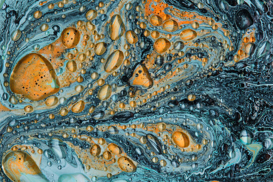 Intricate liquid background showing orange and dark grey fluid art covered with clear oil drops.