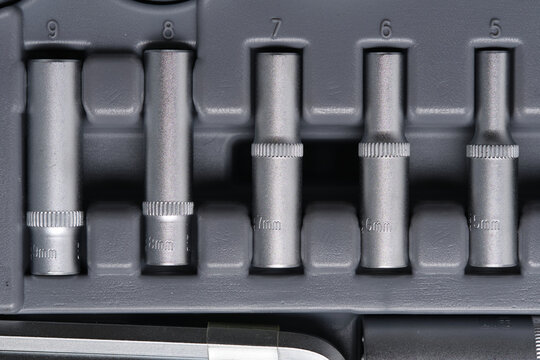 Row metric metal extension sockets sorted by size in gray molded plastic tool container.
