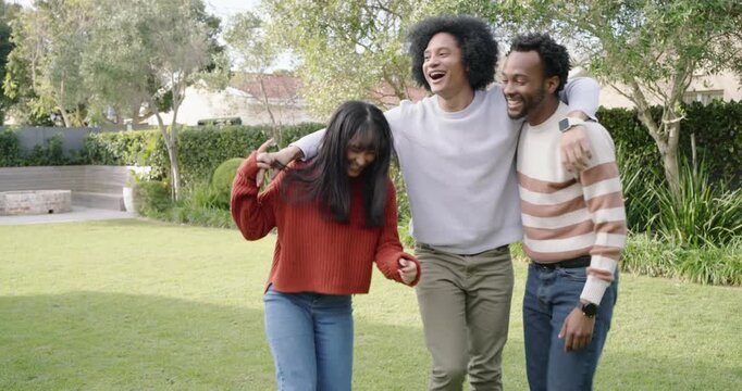 African American friends lifting center friend after side reaching, posing in knit sweaters on lawn