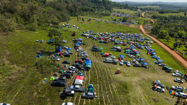 Aerial view of Rally Paraguay 2026 with numerous cars and colorful tents set up on a grassy hillside in Nueva Alborada, Itapua Department, Paraguay.