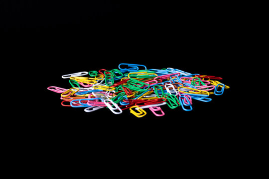 Pile of scattered colorful paper clips isolated on a plain black background