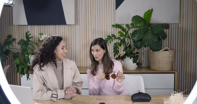 Diverse female hosts retrieving round shades from product box on studio set, showing hinge and lens