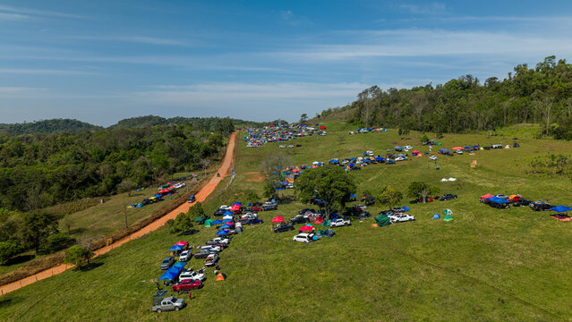 Aerial view of Rally Paraguay 2026 with spectators camping in colorful tents along a dirt road in a grassy field in Nueva Alborada, Itapua Department, Paraguay.