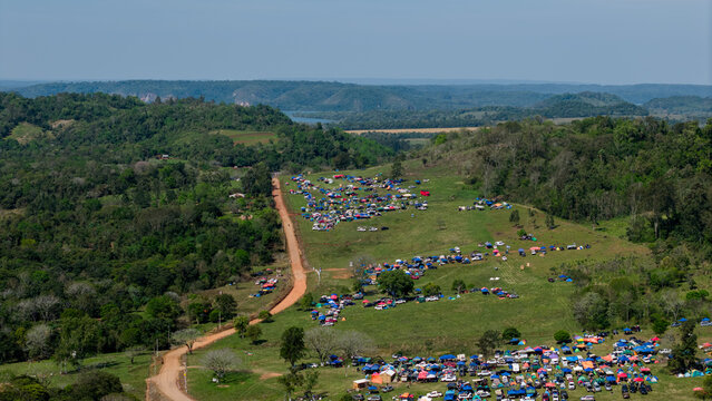 Aerial view of Rally Paraguay 2026 spectator camping area with colorful tents and vehicles on a green hillside near a dirt road in Nueva Alborada, Itapua Department, Paraguay.