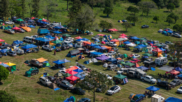 Aerial view of Rally Paraguay 2026 campsite featuring numerous colorful tents, vehicles, and campers spread across a grassy field in Nueva Alborada, Itapua Department, Paraguay.