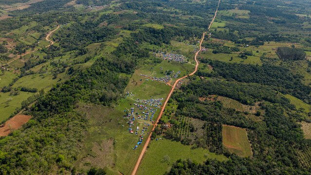 Aerial view of Rally Paraguay 2026 with spectators camping along the dirt road in the rolling hills of the countryside in Nueva Alborada, Itapua Department, Paraguay.