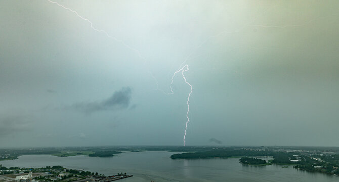 Aerial view of a powerful lightning strike illuminating the dark, stormy sky over the coastal waters and urban landscape of Helsinki, Uusimaa, Finland.