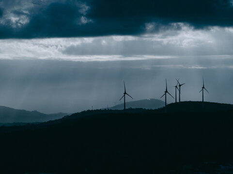 Aerial view of wind turbines on rolling hills under a dramatic stormy sky in Santo Isidoro, Lisboa, Portugal.
