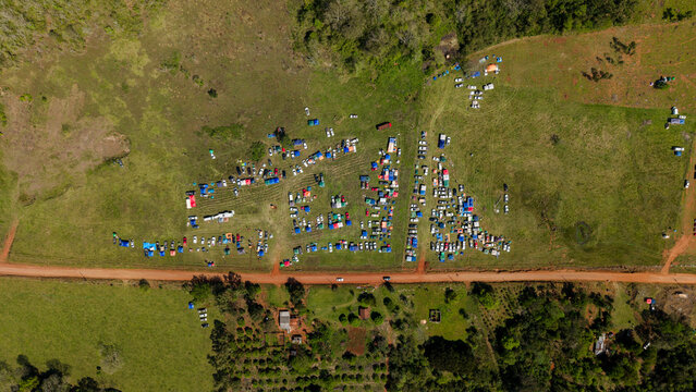 Aerial view of Rally Paraguay 2026 with numerous spectator vehicles parked in grassy fields along a dirt road in the rural landscape of Nueva Alborada, Itapua Department, Paraguay.