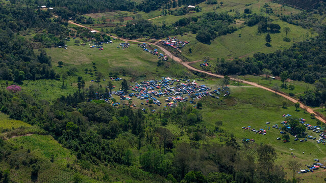 Aerial view of Rally Paraguay 2026 with numerous spectator vehicles parked in green fields along dirt roads in the rural landscape of Nueva Alborada, Itapua Department, Paraguay.