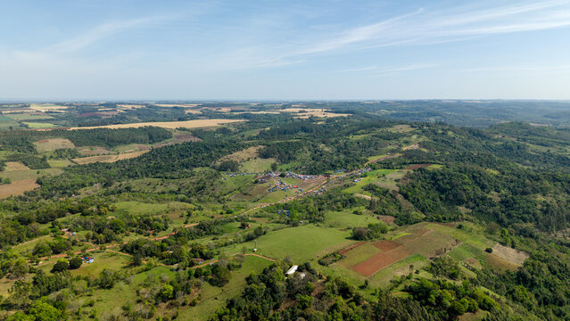 Aerial view of Rally Paraguay 2026 event site with tents along a dirt road winding through rolling green hills and agricultural fields in Nueva Alborada, Itapua Department, Paraguay.