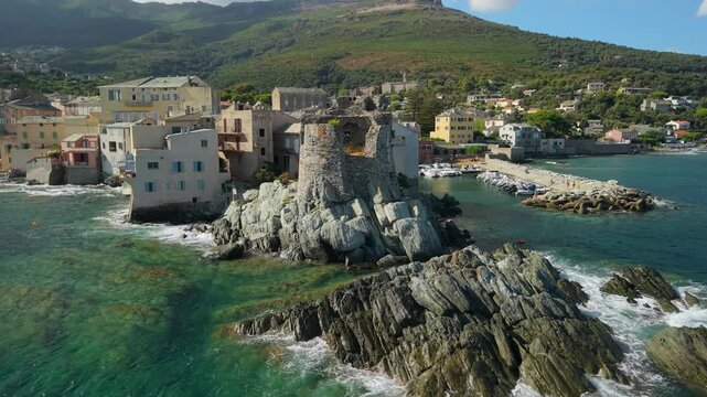 Erbalunga coastal village aerial drone flyover from Genoese tower to marina Corsica. Dynamic rotation over boats and colourful houses turquoise sea cinematic 4K footage