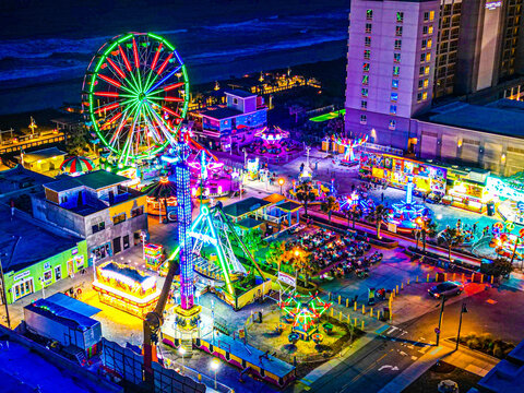 Aerial view of the Carolina Beach Boardwalk Amusement Park at night, featuring a glowing Ferris wheel and vibrant amusement rides in Carolina Beach, North Carolina, United States.