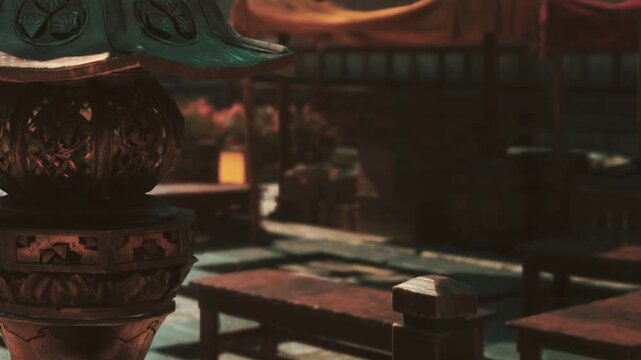 A stone lantern sits in a garden area during daytime. Wooden tables are arranged along the walkway. Flowers are visible in the background near the seating area.