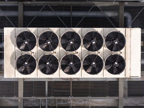 Aerial view of industrial HVAC cooling fans arranged in a grid on a metal rooftop in Gdansk, Poland.