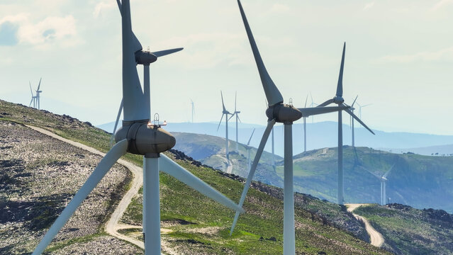 Aerial view of a wind farm with multiple wind turbines across a mountainous landscape, representing renewable energy and clean power. Lisbon, Lisbon, Portugal.