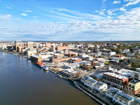 Aerial view of Water Street along the Cape Fear River waterfront featuring historic buildings and riverboats under a blue sky, Wilmington, North Carolina, United States.
