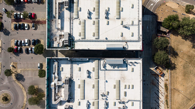 Aerial view of rooftop HVAC equipment serving a commercial building, showing ventilation ducts, cooling units, and mechanical infrastructure for climate control in Assago, Lombardy, Italy.