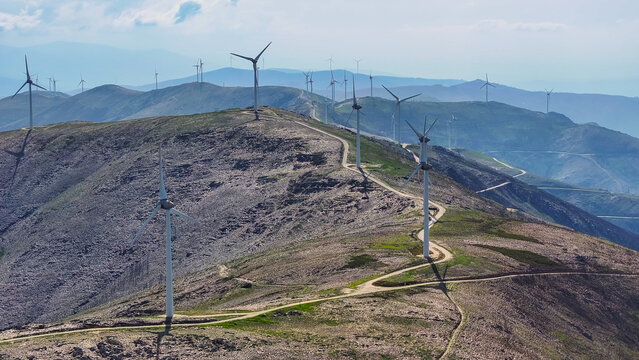 Aerial view of a wind farm with multiple wind turbines situated along a rocky mountain ridge, showcasing renewable energy infrastructure. Lisbon, Lisbon, Portugal.
