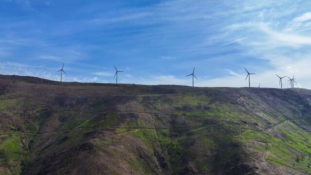 Aerial view of a wind farm with multiple wind turbines across a mountainous landscape, representing renewable energy and clean power in Lisbon, Lisbon, Portugal.