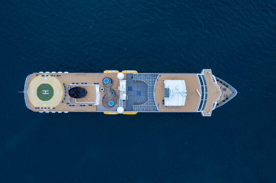 Rathlin Island, Northern Ireland, United Kingdom - 14 July 2022: Aerial view of a cruise ship on the open sea with a helipad, swimming pools, and wooden decks visible from above.