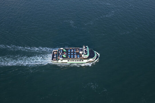 Gosport, United Kingdom - 21 July 2021: Aerial view of a passenger ferry crossing the dark blue water, leaving a white wake behind it.