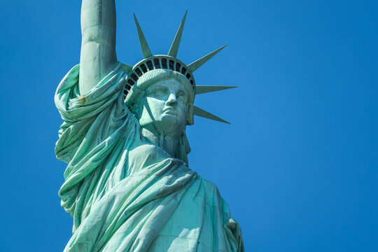 UNITED STATES, NEW YORK CITY, LIBERTY ISLAND. CLOSE-UP VIEW OF THE ICONIC STATUE OF LIBERTY, HIGHLIGHTING THE FACE, CROWN, AND DRAPERY OF THE COPPER-CLAD SCULPTURE. SYMBOLIC AMERICAN MONUMENT