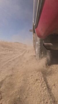 Vehicle drives through dusty desert trail