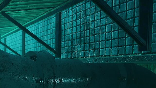 Rusty pipelines and weathered walls rise from the sea floor, illuminated by cool blue light. A haunting beauty captivates as shadows dance and history whispers tales of industry long forgotten.