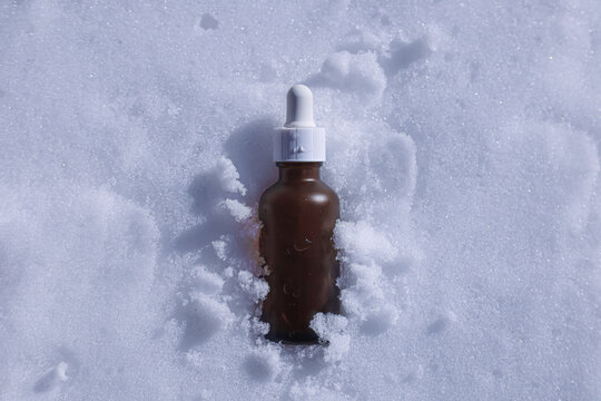 Brown glass dropper bottle in white snow