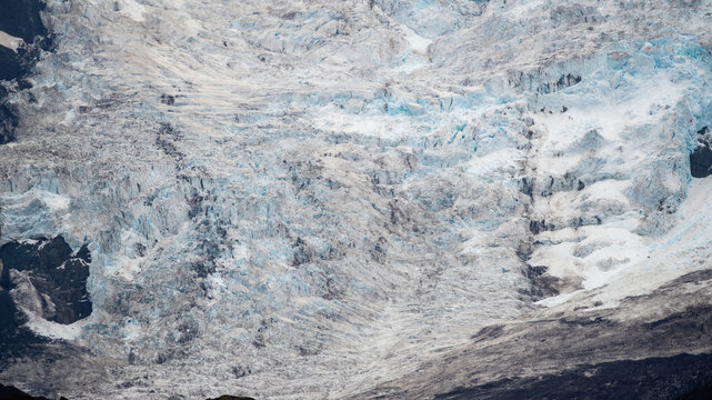 A vast Vatnajokull Glacier flowing down a mountain in Iceland, forming a long winding ice ridge that stretches for several kilometers across the rugged landscape.