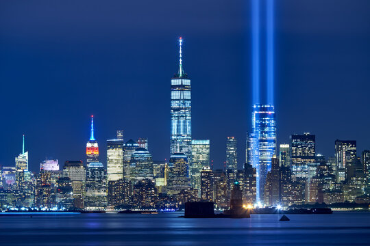 UNITED STATES, NEW YORK CITY, MANHATTAN, LOWER MANHATTAN. THE TWO BEAMS OF THE TRIBUTE IN LIGHT WITH SKYCRAPERS OF FINANCIAL DISTRICT AT NIGHT WITH THE EMPIRE STATE BUILDING INTHE DISTANCE