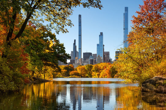 UNITED STATES, NEW YORK CITY, MIDTOWN MANHATTAN. CENTRAL PARK IN AUTUMN BY THE LAKE WITH VIEW OF BILLIONAIRES' ROW SKYSCRAPERS STEINWAY TOWER ON LEFT, ONE57 IN CENTER AND CENTRAL PARK TOWER RIGHT
