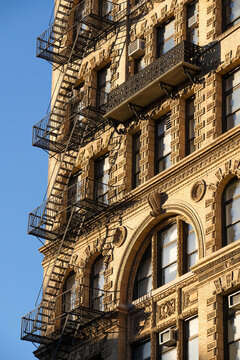 UNITED STATES, NEW YORK CITY, MANHATTAN, CHELSEA. FIRE ESCAPE AND ORNAMENTED FACADE WITH WROUGHT IRON BALCONY ON BRICK BUILDING IN CHELSEA