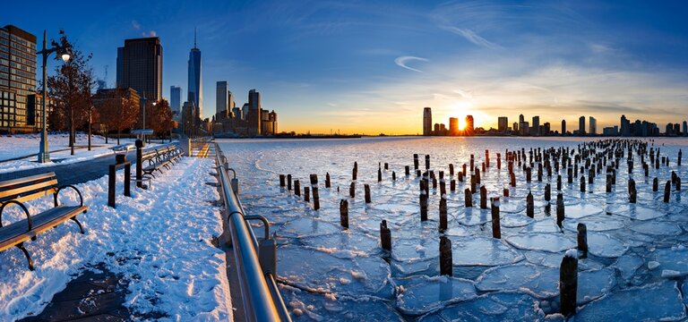 UNITED STATES, NEW YORK CITY, MANHATTAN, LOWER MANHATTAN. PANORAMIC SUNSET ON THE HUDSON RIVER COVERED IN ICE, NEW YORK OLD PIER PILINGS WITH A VIEW OF ONE WORLD TRADE CENTER AND DOWNTOWN JERSEY CITY