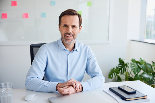 Confident businessman smiling at desk in modern office