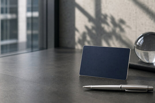 Minimalist business card mockup on dark stone desk. Professional stationery template with silver pen. Modern office workspace with glass sphere.