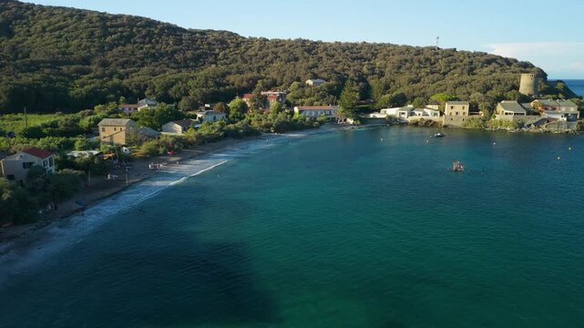 Marine de Meria Corsica drone golden hour Genoese tower flyover circular beach traditional coastal village late afternoon warm light Cap Corse rocky shore